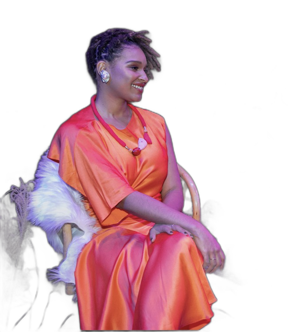 Dyandra Raye seated in a coral-orange look